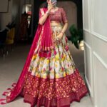 Woman wearing a vibrant Traditional Bandhani Chaniya Choli set with a rani pink blouse, floral lehenga, and matching dupatta from Pramukhmart.