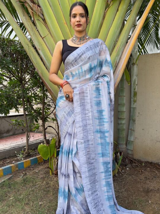 One Min Ready to Wear Saree with Blouse" from Pramukhmart, posing outdoors in front of large green palm leaves.